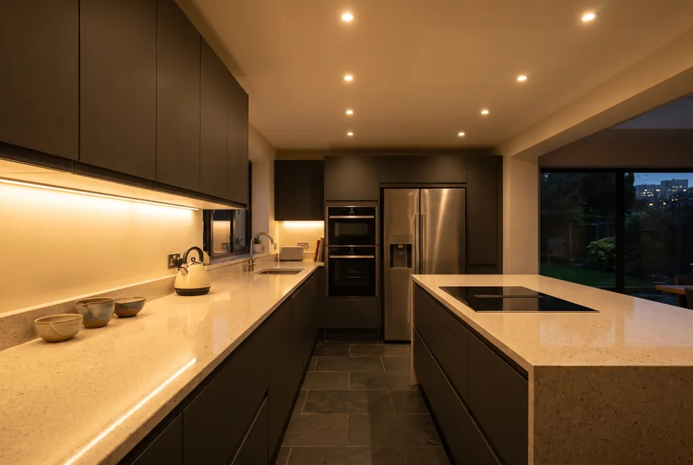 A modern kitchen with downlights and under-cabinet lighting